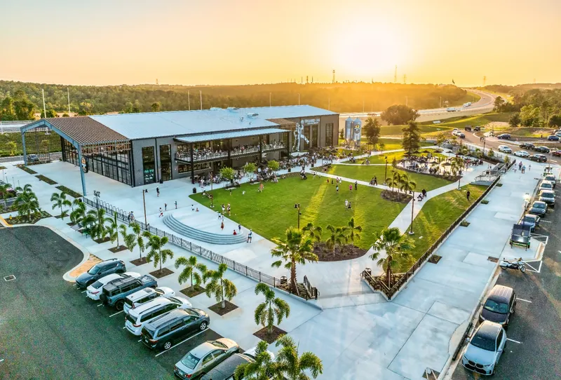 Aerial view at sunset of the Crooked Can Minneola brewery campus with a great lawn, terraces and outdoor seating